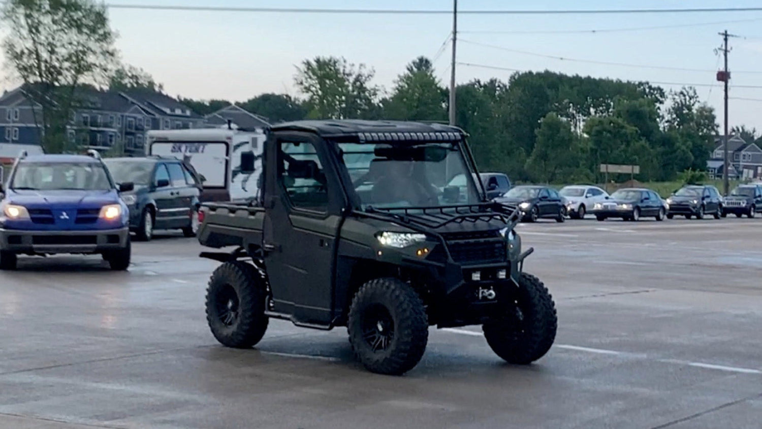Black off-road vehicle on a road with traffic lights and buildings in the background